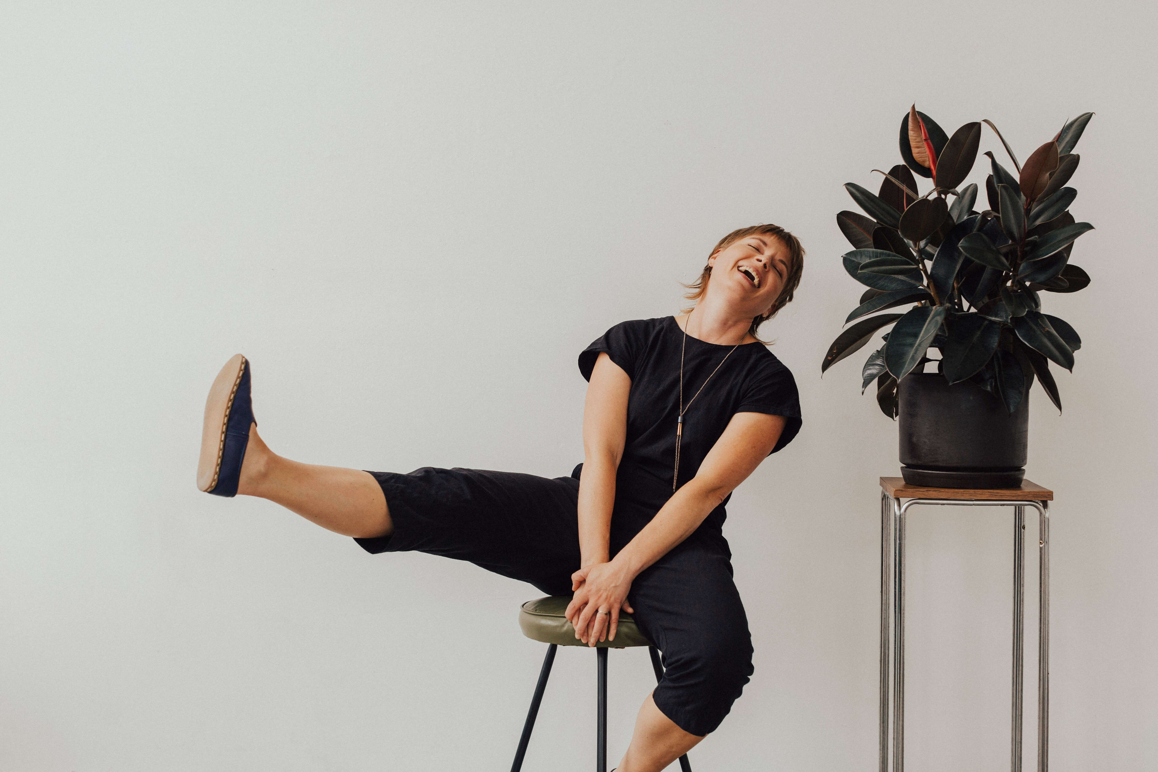 Greeting Cards maker Queen Fayzel sitting on a stool smiling and kicking one leg