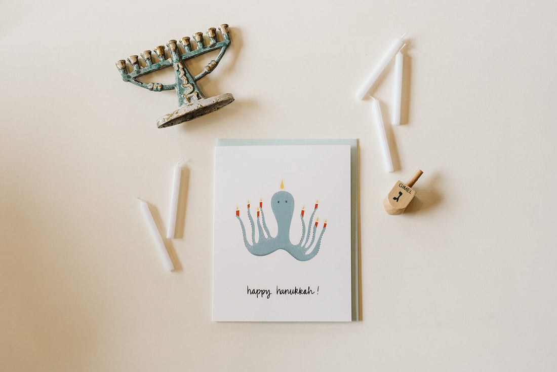 Happy Hanukkah card with a light blue octopus holding candles like a menorah