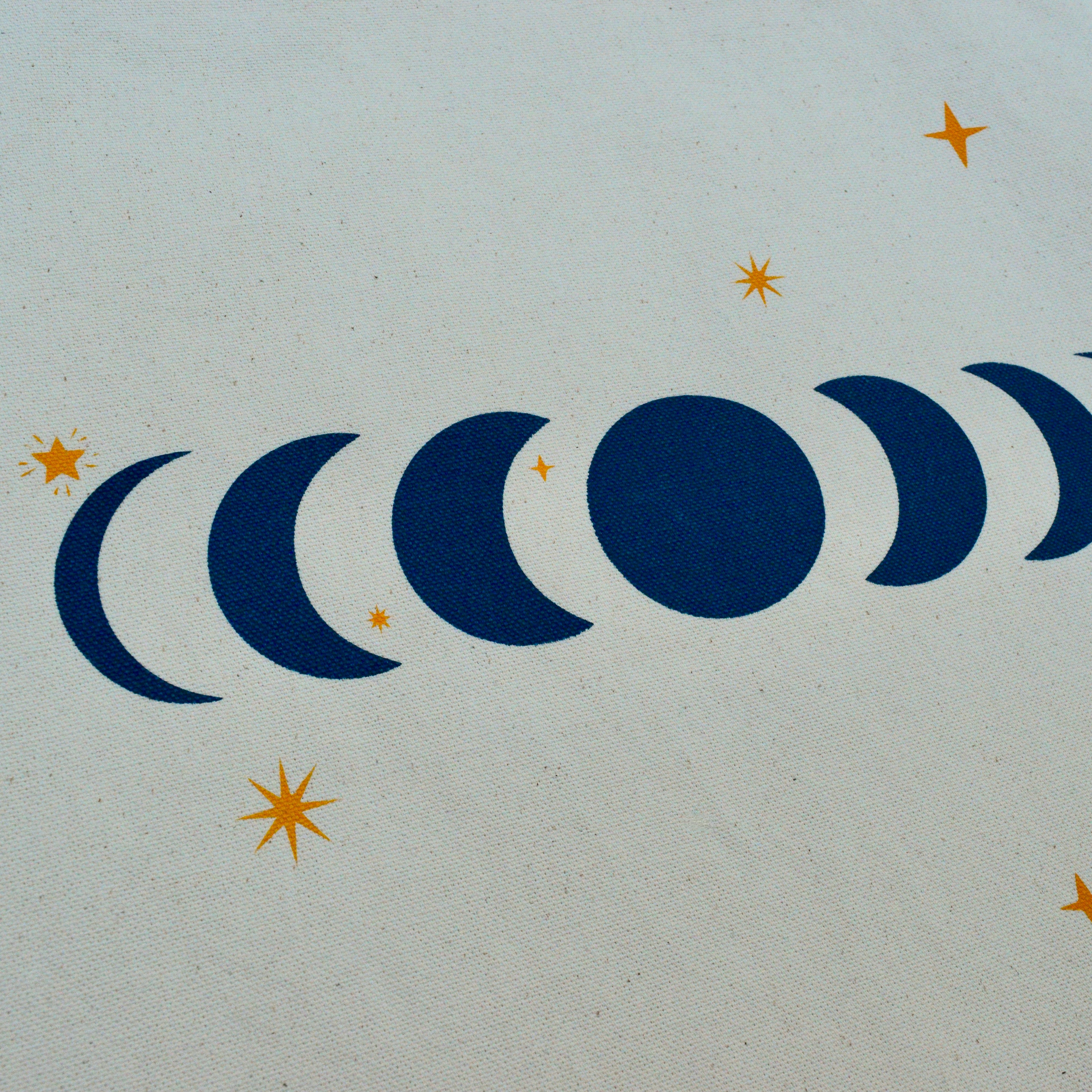 closeup detail of a moon phases design with star shapes on a canvas tote bag