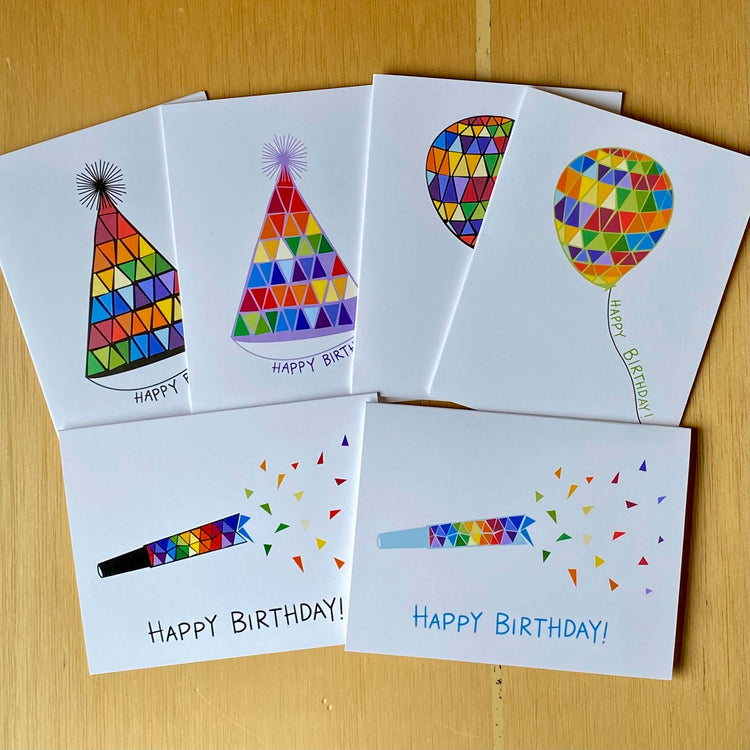 Collection of birthday cards with rainbow balloons, party hats, and noisemakers.