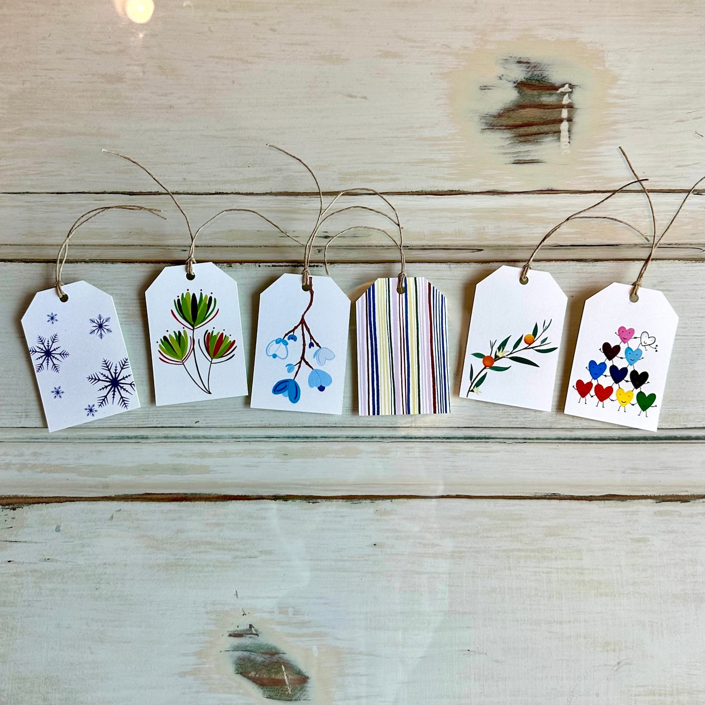 collection of gift tags with hemp string, against a white wooden background