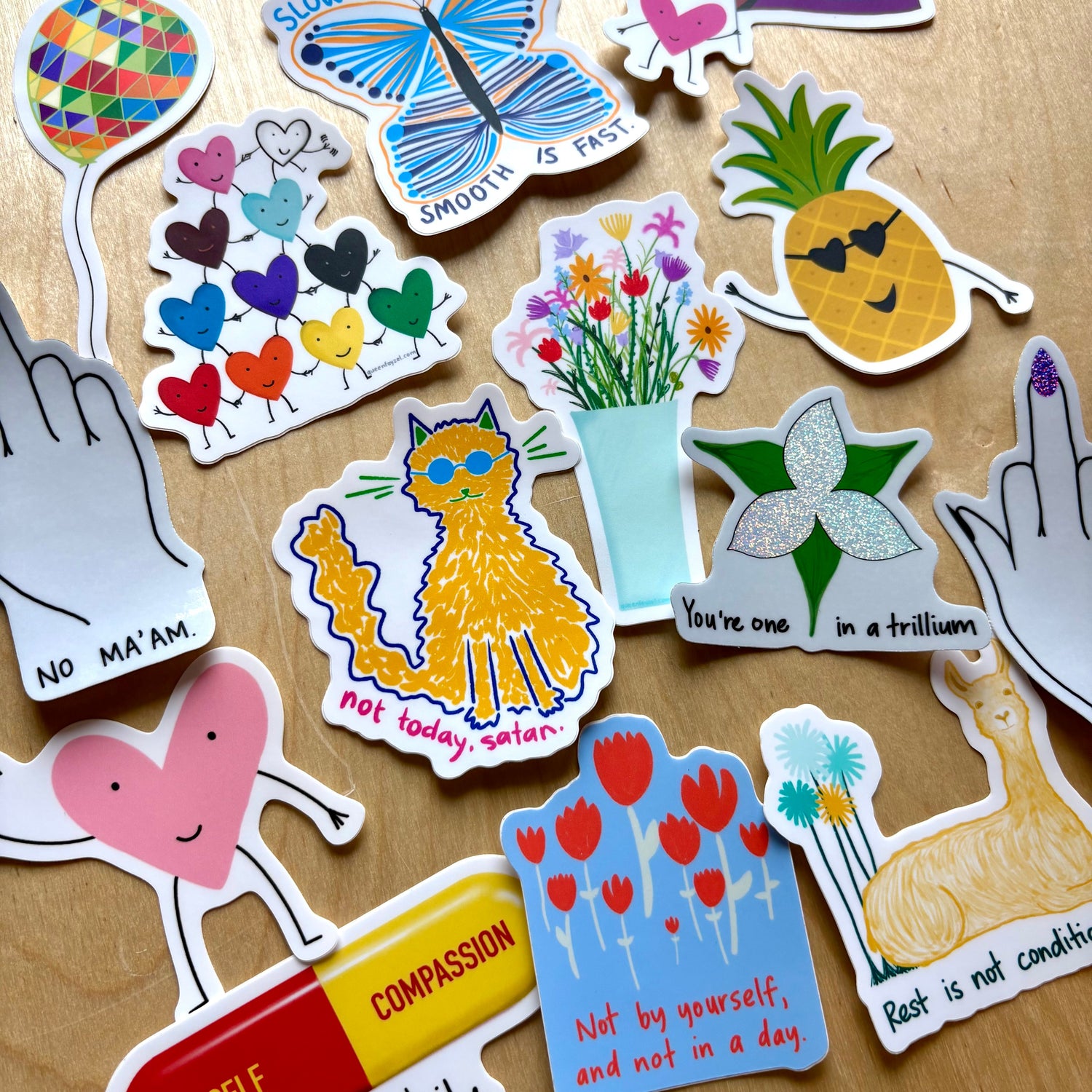 Brightly colored funny, cute, inspirational vinyl stickers against a wooden background