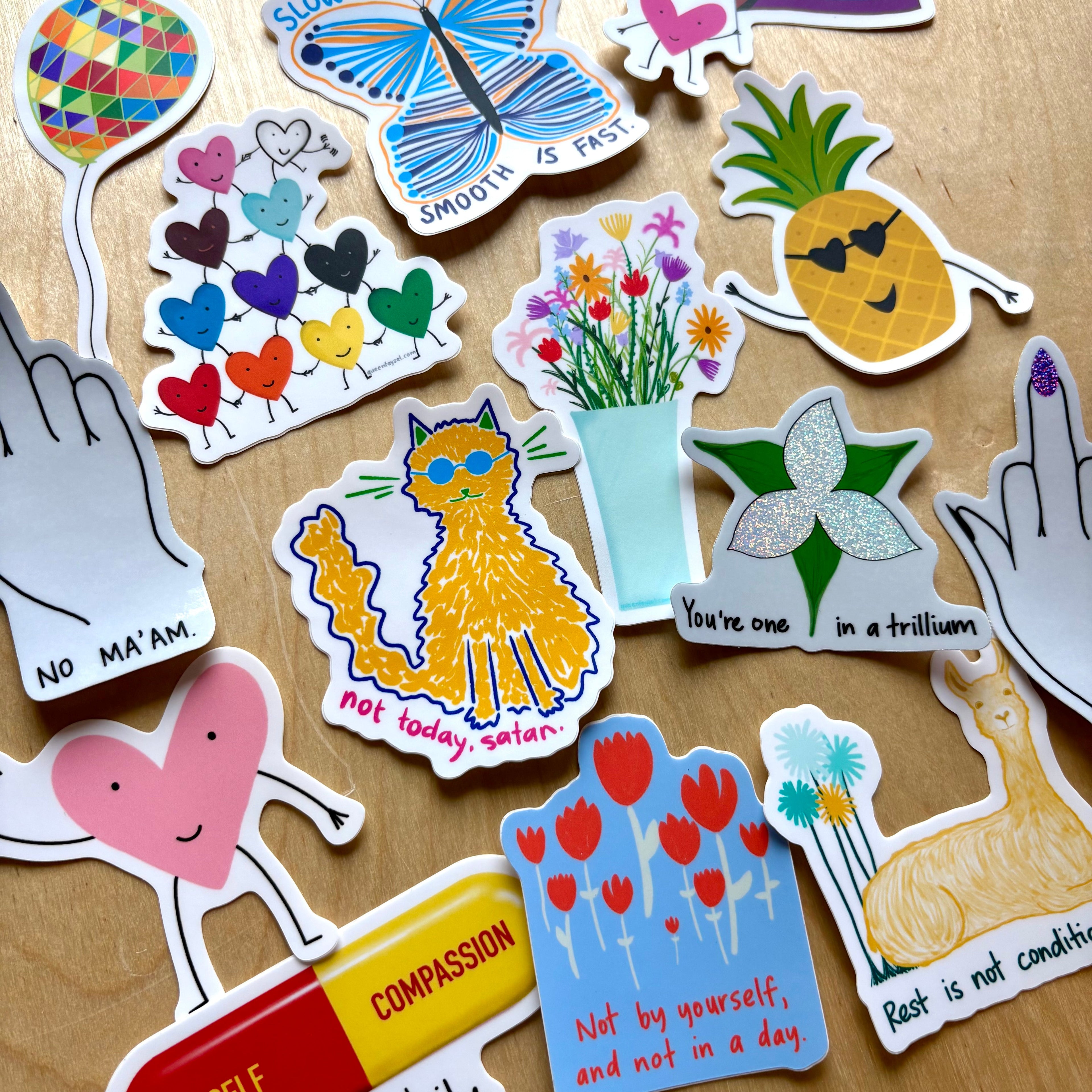 Brightly colored funny, cute, inspirational vinyl stickers against a wooden background