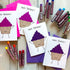 pink and purple glitter cupcake birthday cards scattered on a table with oil pastels.