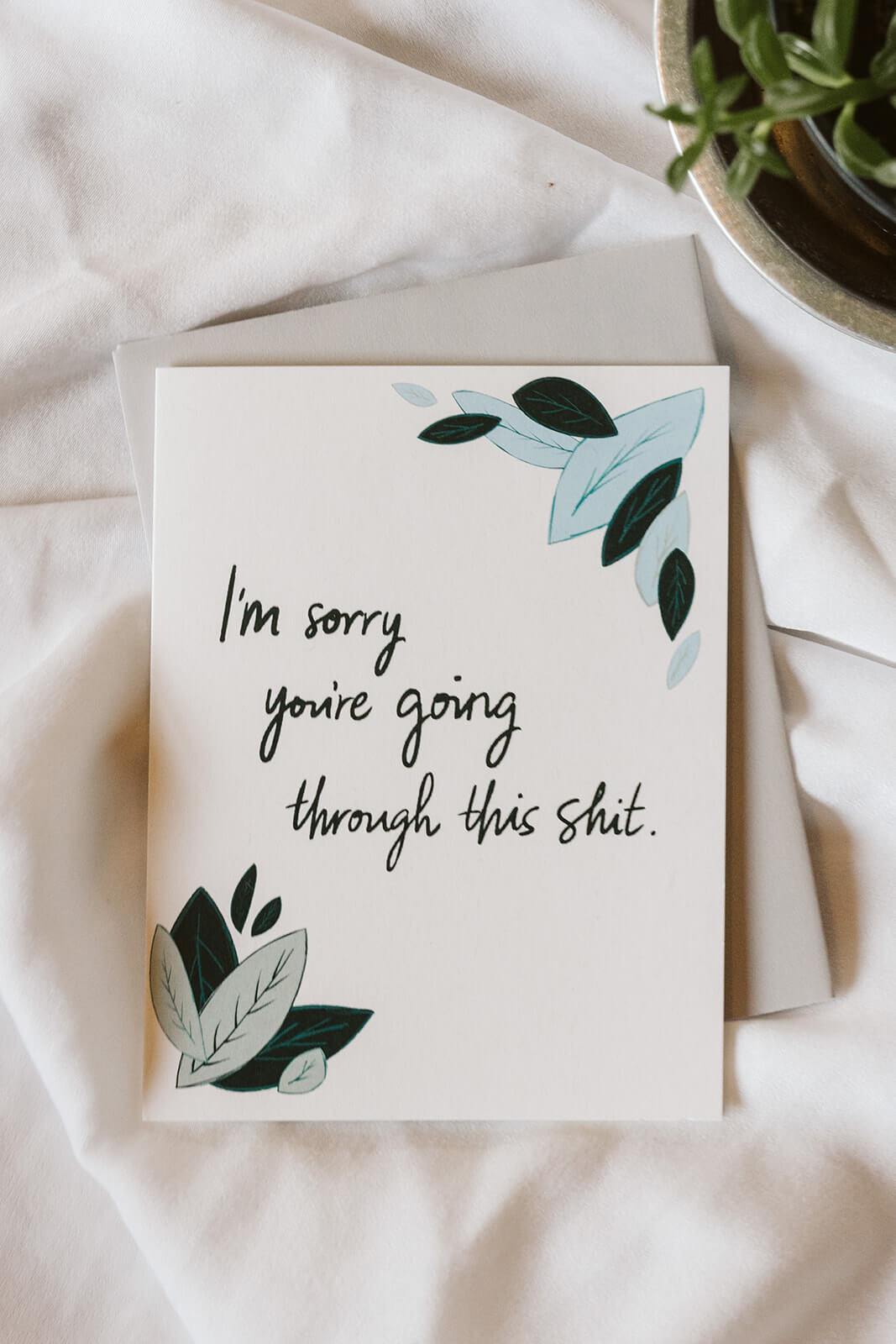An encouragement card with light blue and sage green leaves and text reading "I&