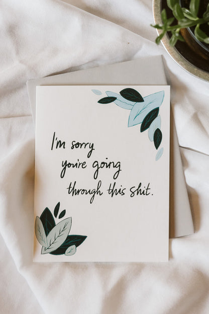 An encouragement card with light blue and sage green leaves and text reading "I&