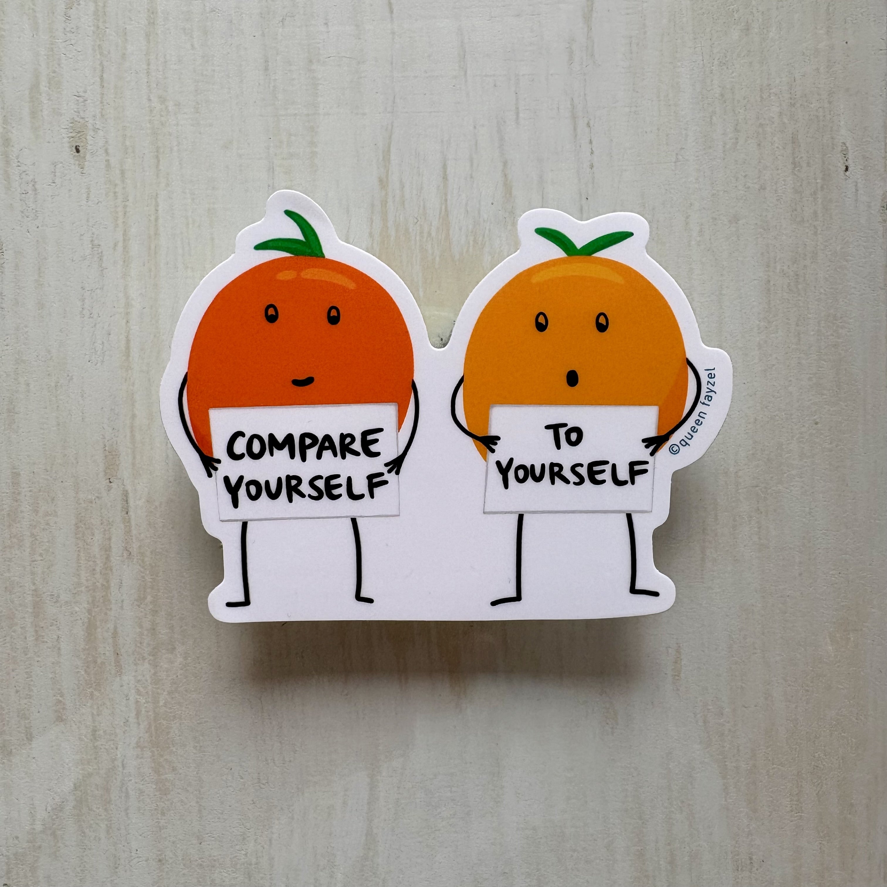 Two cartoon oranges holding signs with motivational text on a wooden surface