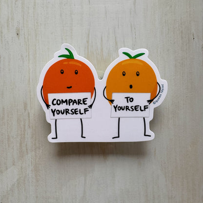 Two cartoon oranges holding signs with motivational text on a wooden surface