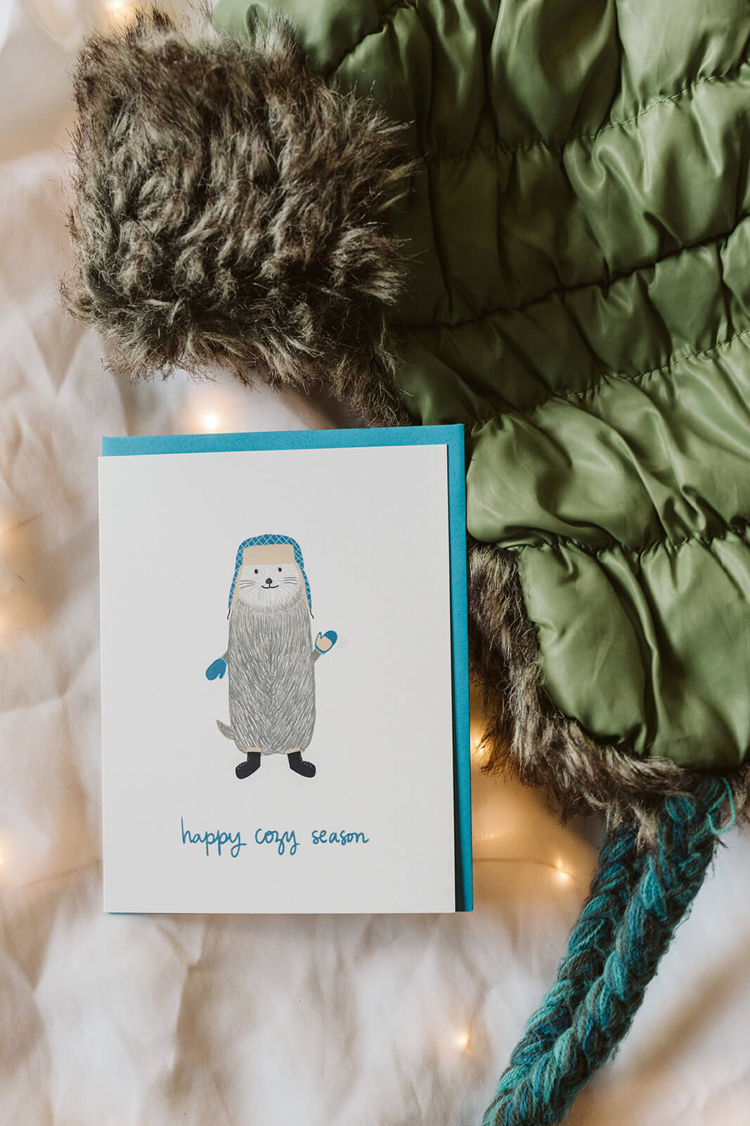 seasons greetings card with otter bundled in winter gear