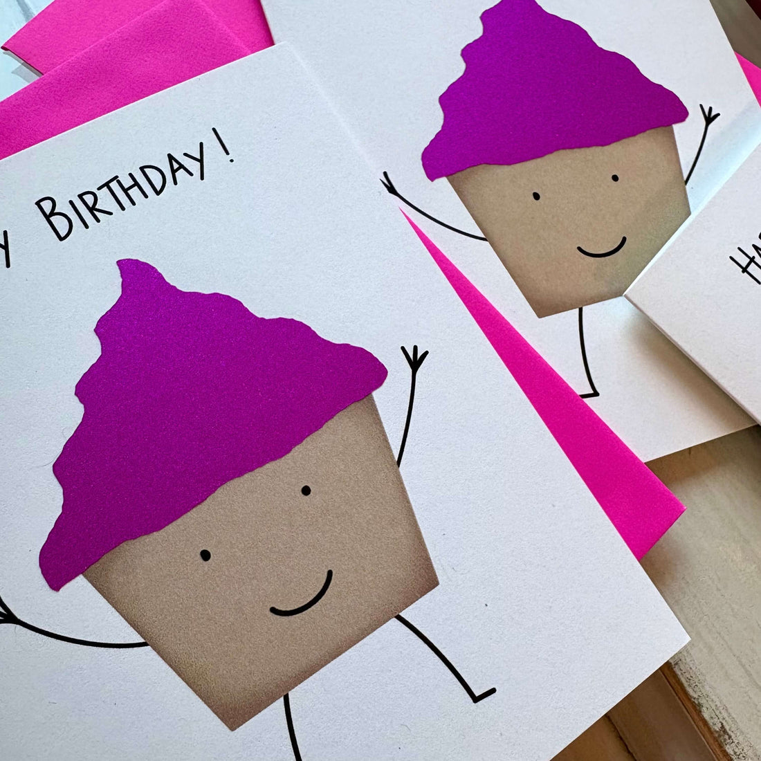 Birthday card with cupcake character wearing pink glitter frosting on a white background