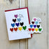 A greeting card and a sticker showing a cute pyramid of rainbow-colored hearts holding hands.