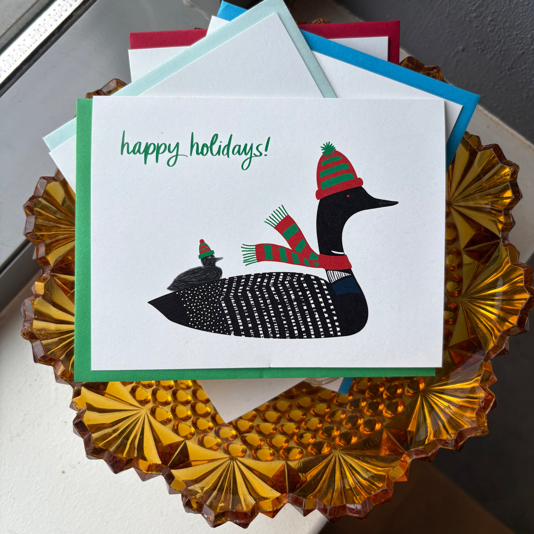Greeting card with a loon illustration wearing a hat and scarf, labeled &