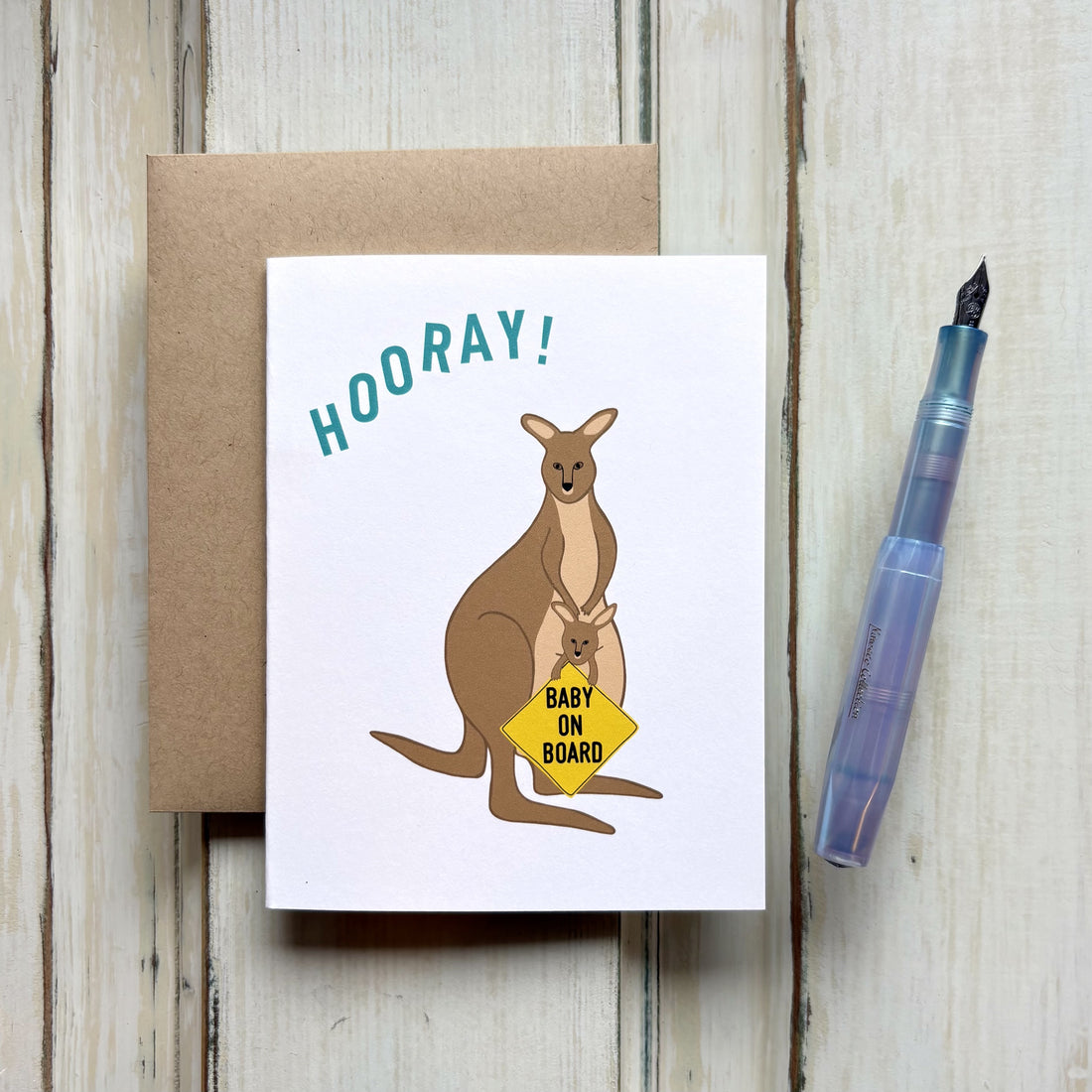 Baby shower card with a kangaroo with a joey in the pouch holding a yellow "Baby on Board" sign, with "HOORAY!" in teal above.