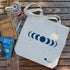 canvas tote bag with moon phase design styled on a wooden table with a water bottle, journal, and pen