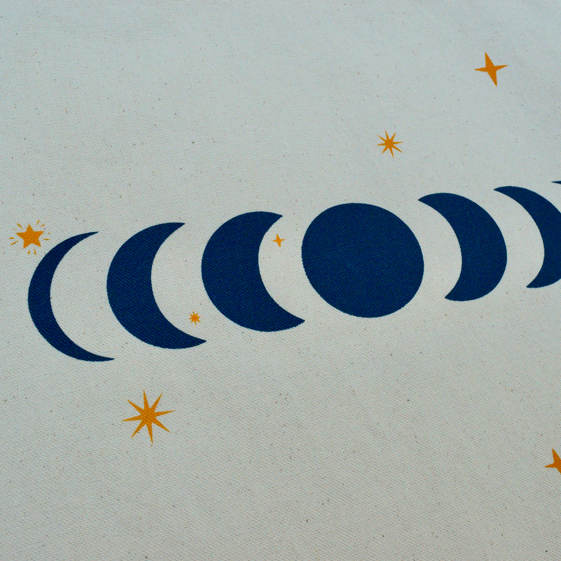 closeup detail of a moon phases design with star shapes on a canvas tote bag