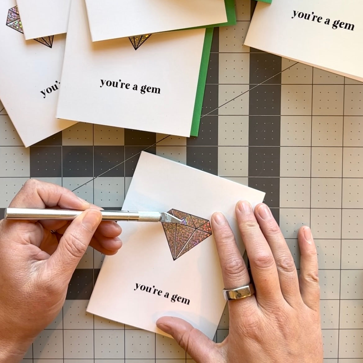 Load video: Short video showing how silver glitter foil is added to a geometric gem shape on a greeting card. The card has the text, &quot;you&#39;re a gem.&quot;