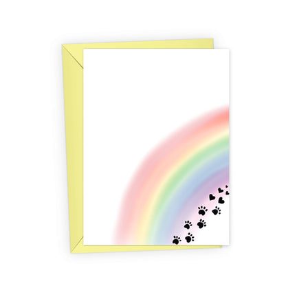 This pet loss sympathy card features a soft watercolor rainbow with paw prints that transition into black hearts. Paired with a yellow envelope.