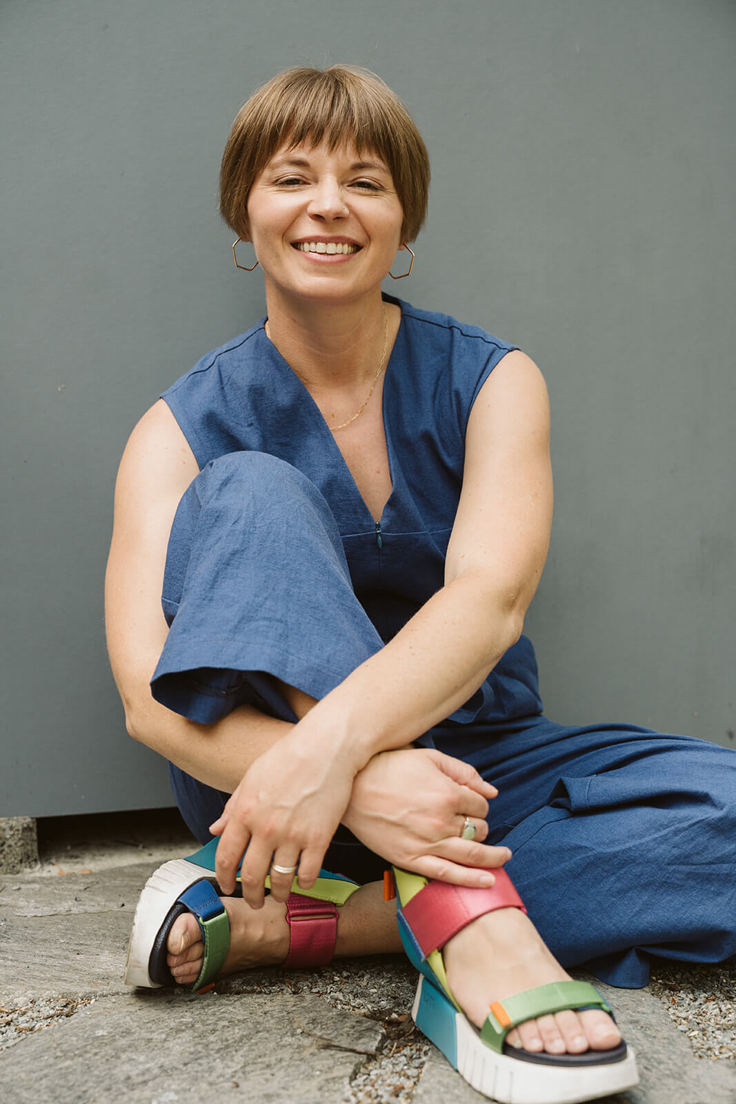 Faye of Queen Fayzel sitting with one knee up, smiling at the camera