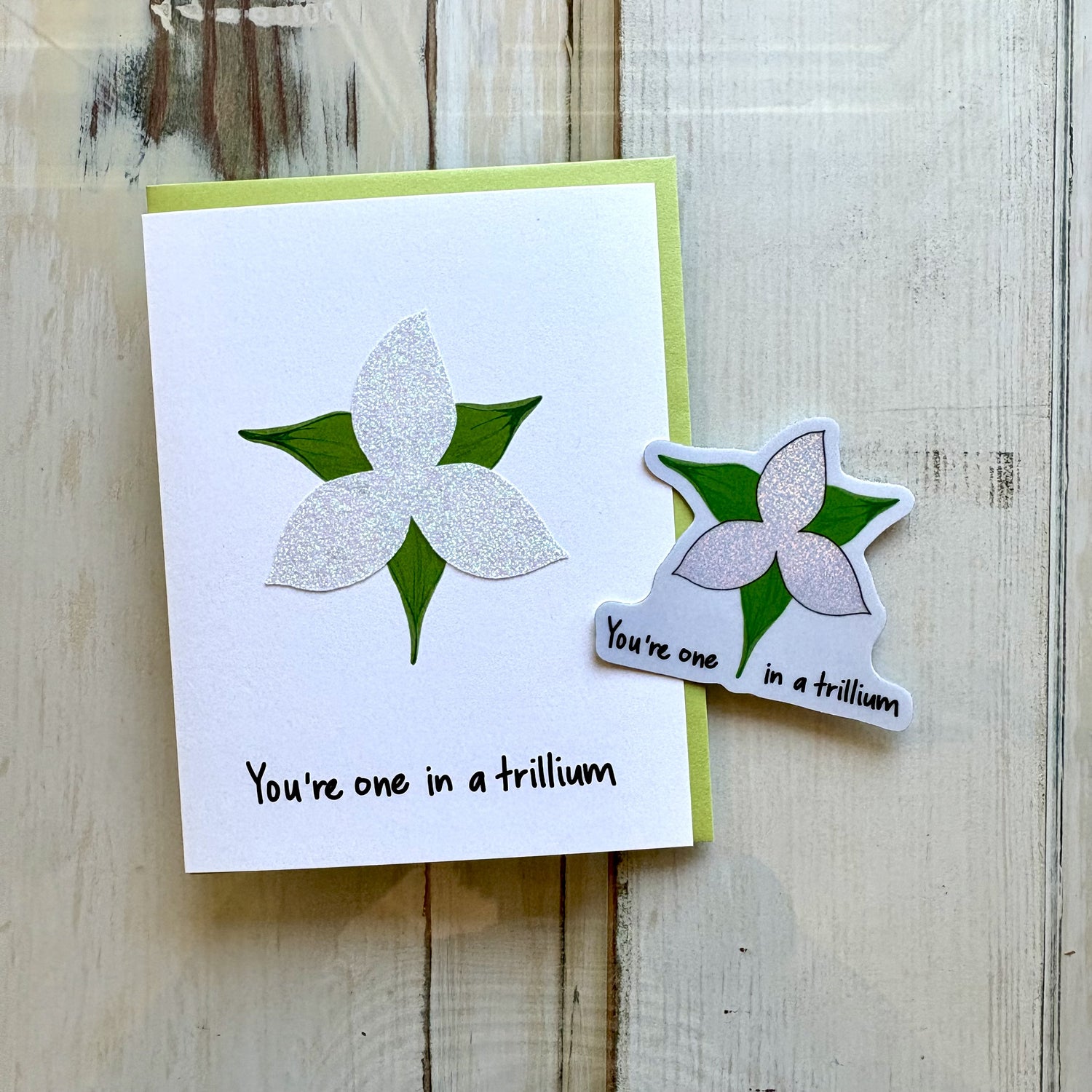 A handmade greeting card and matching sticker featuring a glittery trillium and the text "You&