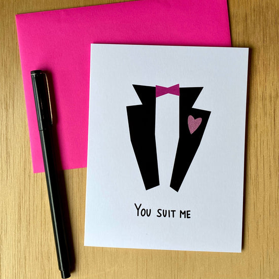Valentine card with a black tux, pink bowtie, and pink glitter heart, with the words, "You suit me."