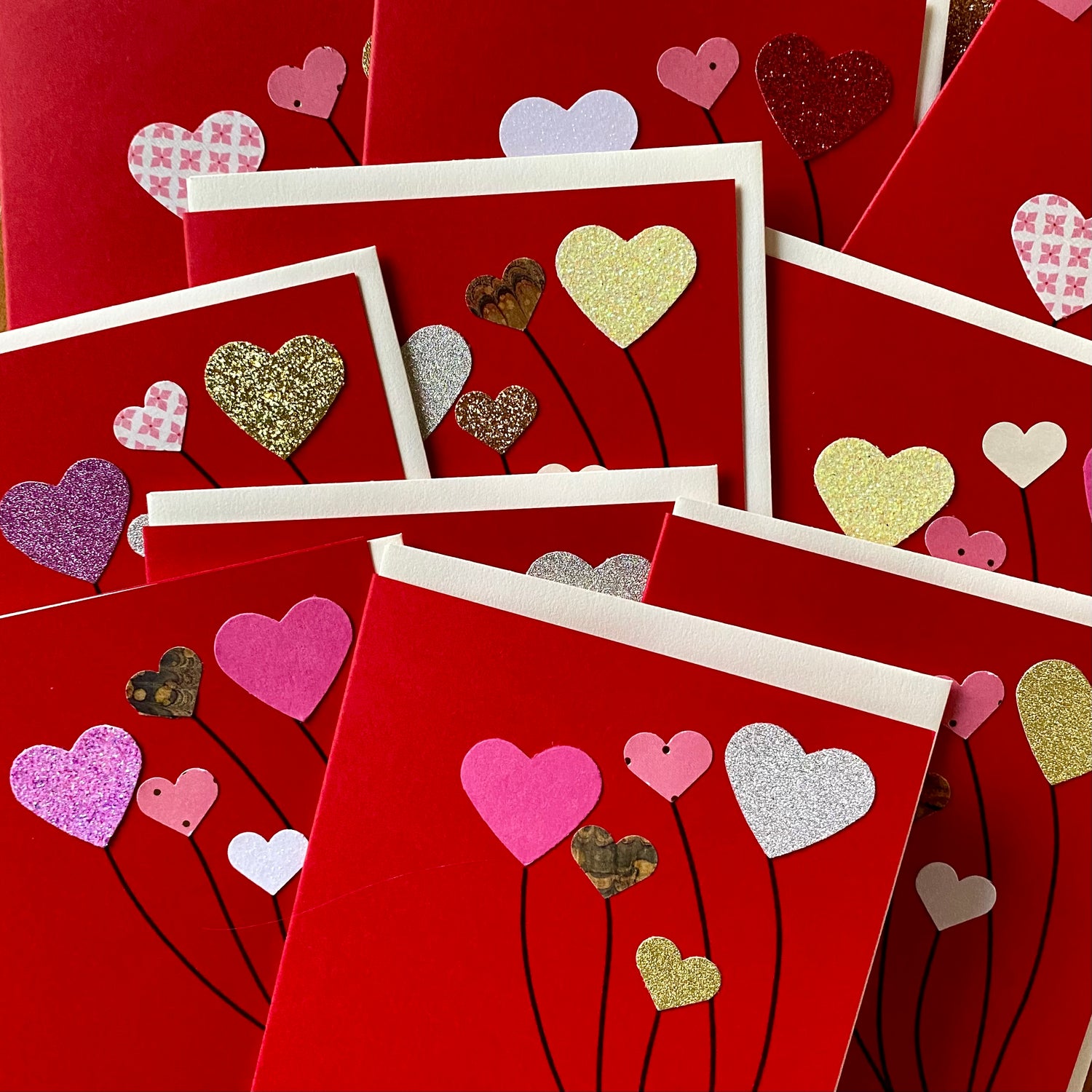 Collection of red Valentine cards, each with hearts in different colors and sizes arranged like balloons