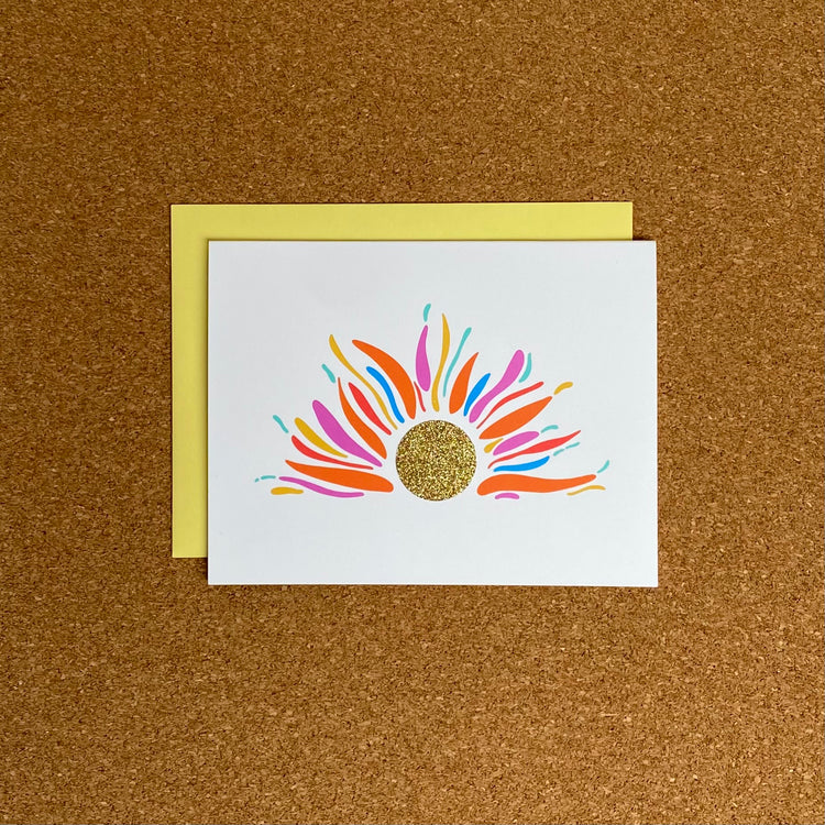 Greeting card with multi-colored rising sun with gold glitter center.