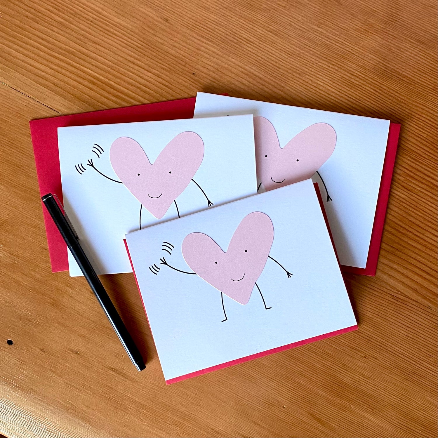 Greeting card with a pink smiling heart with arms & legs, waving.