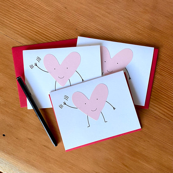 Greeting card with a pink smiling heart with arms & legs, waving.