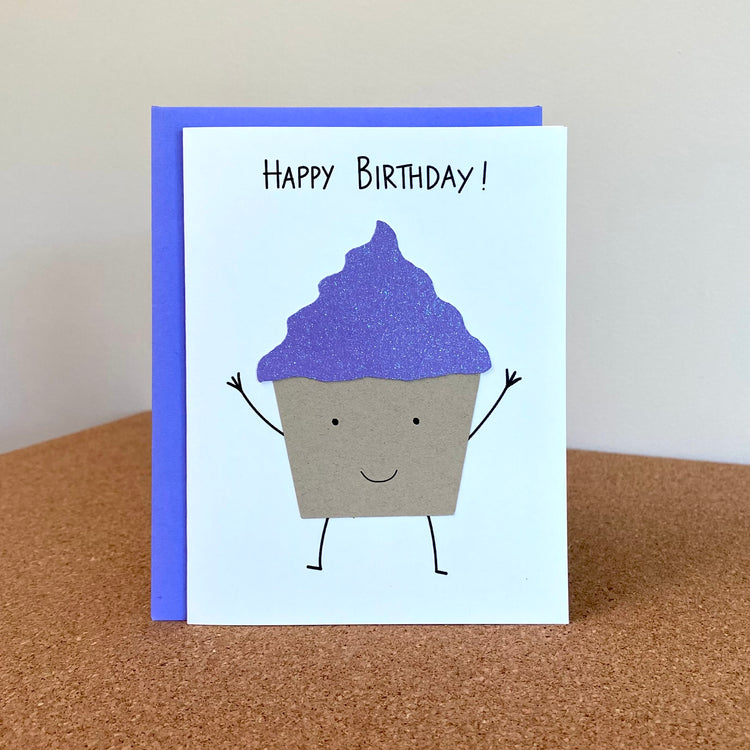 Birthday card with smiling cupcake with purple glitter frosting.