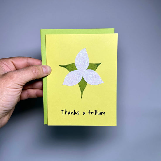 Thank you card on yellow cardstock with a sparkly white trillium and the words, "Thanks a trillium"